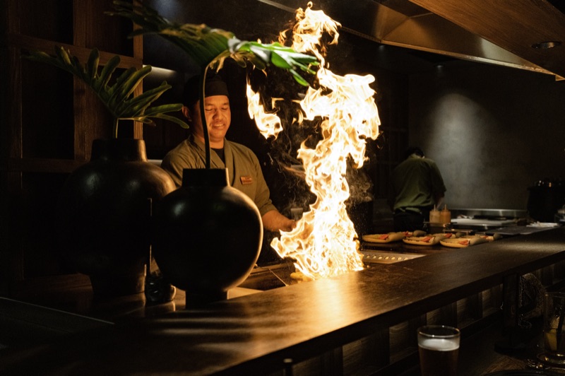 Teppanyaki chef performing flambe with dramatic fire
