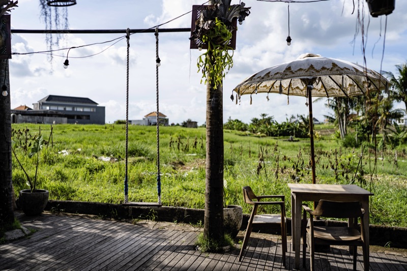Rustic outdoor cafe with Balinese umbrella and rice field
