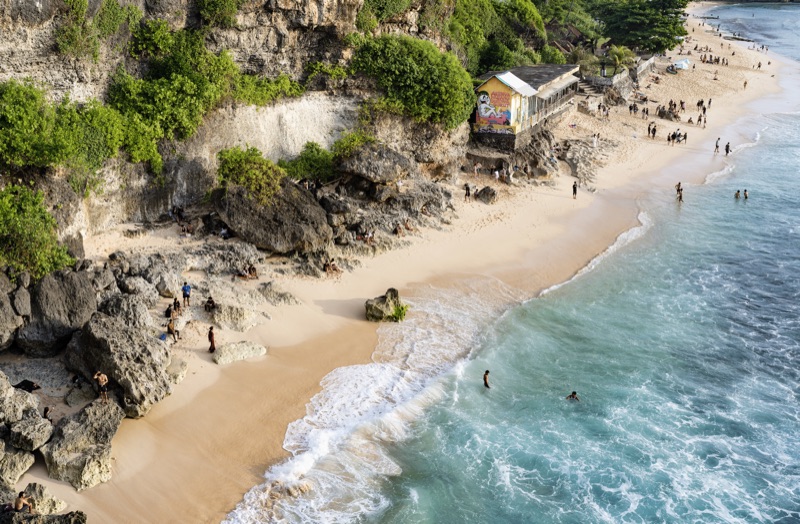Cliff beach with graffiti shack and swimmers