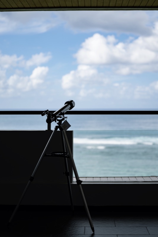 Telescope silhouette on balcony overlooking ocean