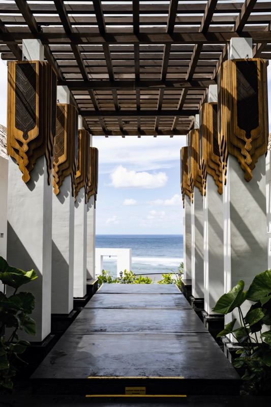 Balinese corridor with carved wooden banners leading to ocean