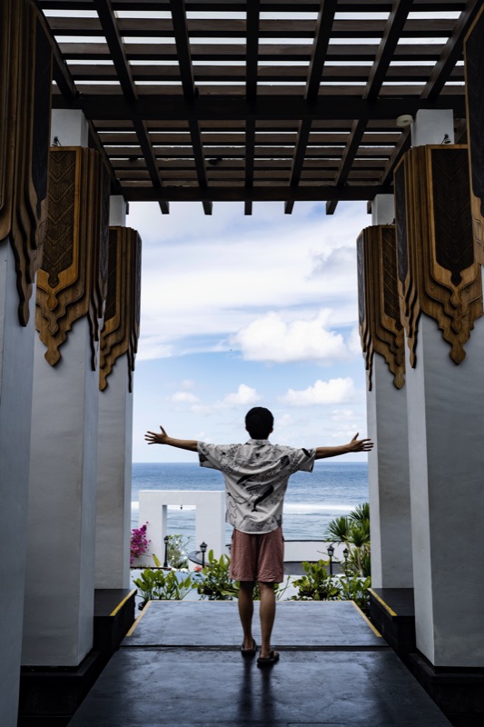 Man with outstretched arms at gateway facing ocean