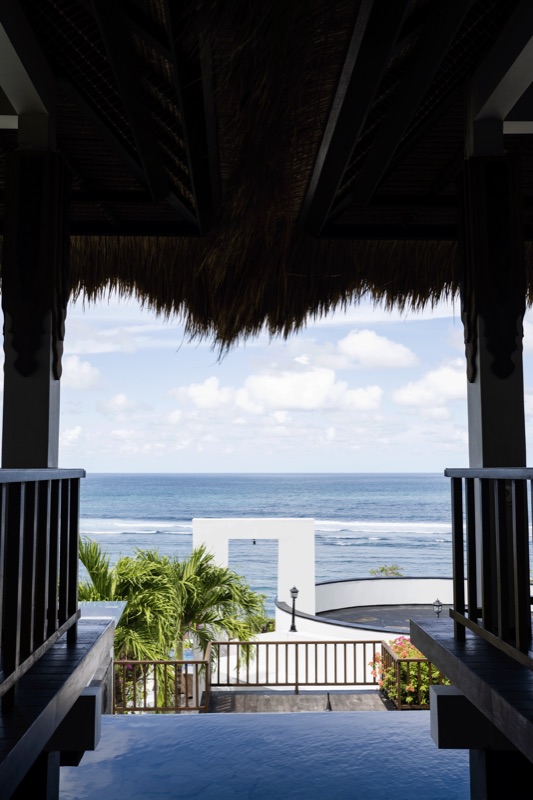 Thatched pavilion framing ocean and white gateway